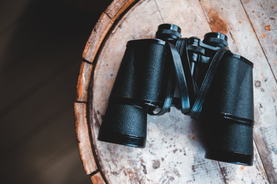 A pair of binoculars on a wooden barrel.